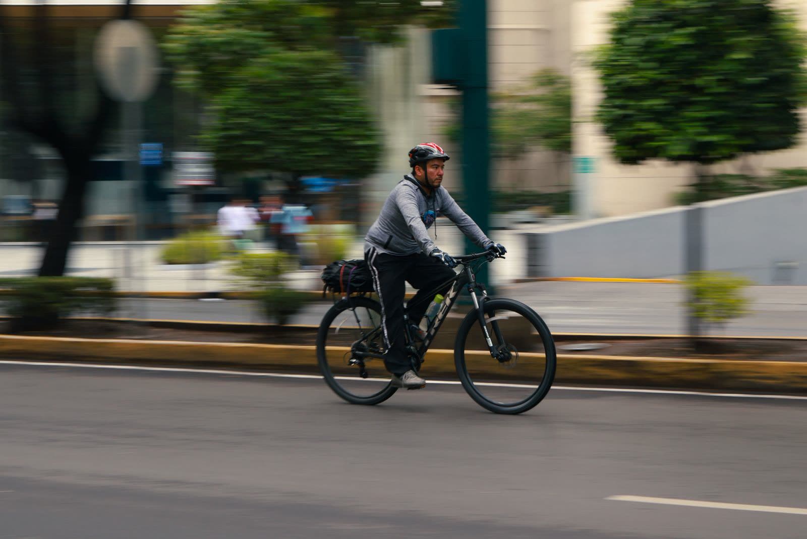 Ciclista urbano pedaleando por una calle arbolada de Coyoacán por la mañana