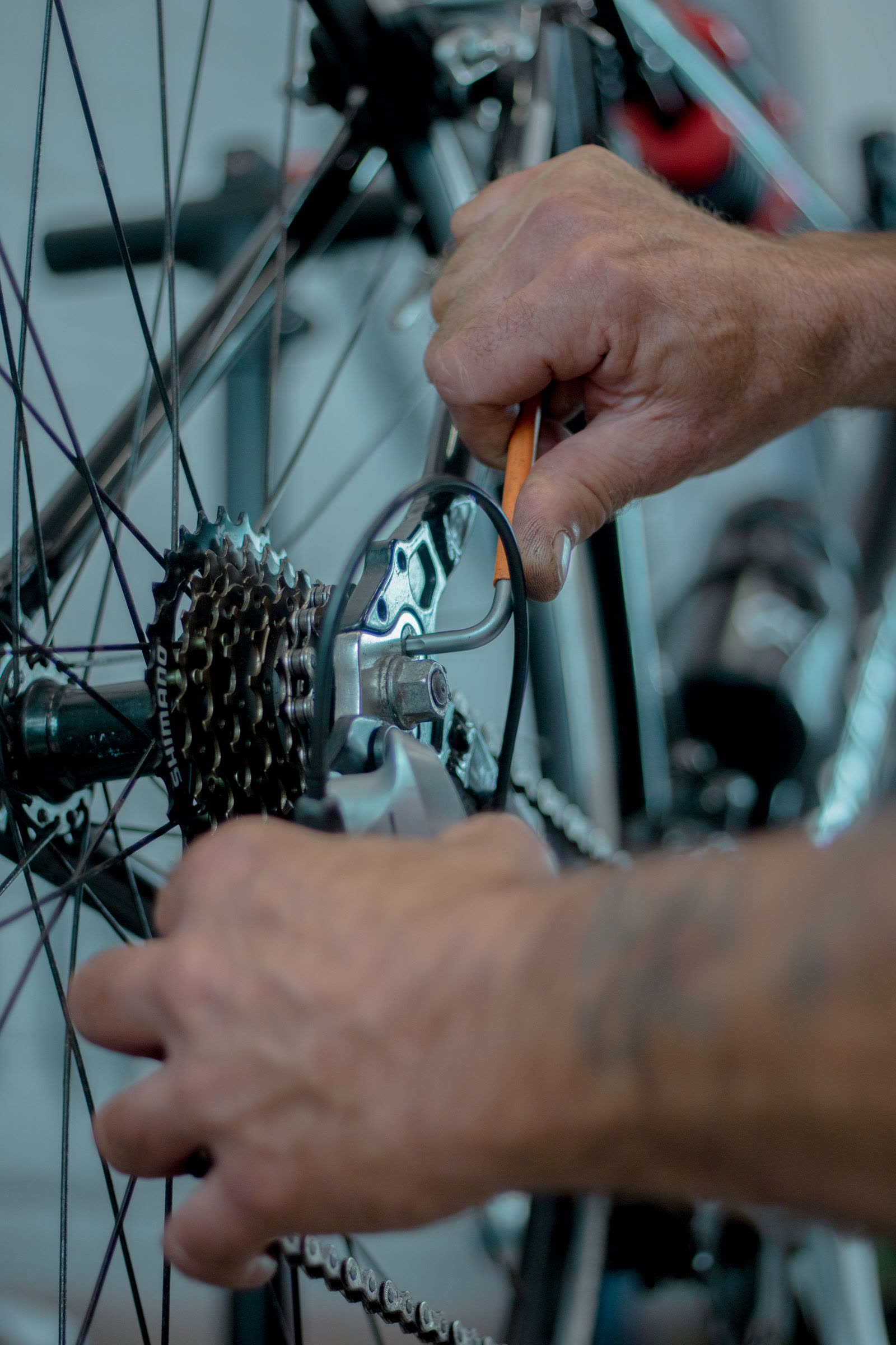 Manos de mecánico ajustando el cambio trasero de una bicicleta